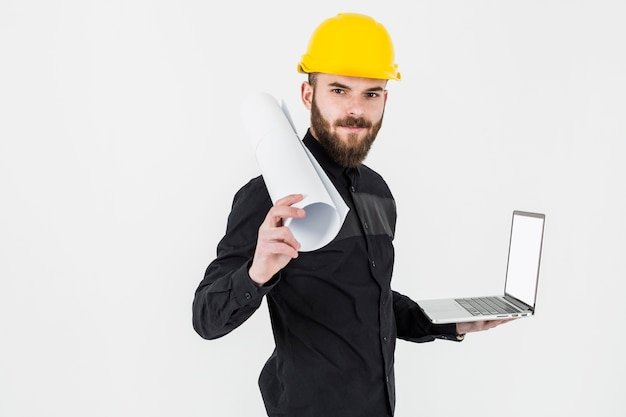 young-engineer-holding-rolledup-blueprint-open-laptop-against-white-backdrop